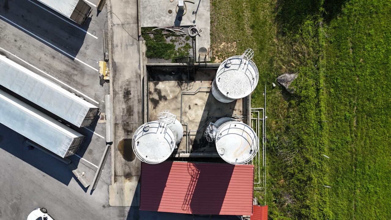 Aerial view of aboveground storage tanks with secondary containment at a commercial truck stop, showing stormwater flow paths and surrounding infrastructure.