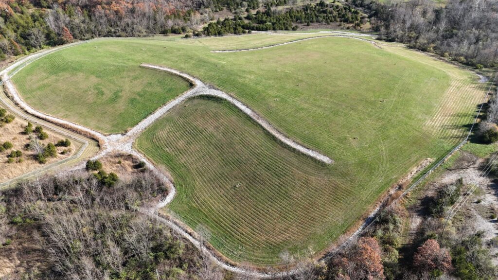 Drone image of a capped landfill at an NPL Superfund site, showing graded cover, perimeter drainage channels, and vegetative stabilization. Drone imagery used for ongoing O&M inspections and regulatory compliance.