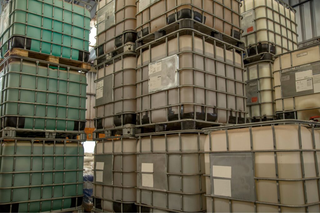 Stacked intermediate bulk containers (IBCs) storing industrial liquids inside a covered facility, demonstrating compliance with NPDES stormwater no exposure certification requirements.